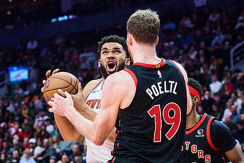 New York Knicks' Karl-Anthony Towns, left, drives to the net past Toronto Raptors' Jakob Poeltl (19) during the second half of an NBA Cup basketball game in Toronto.