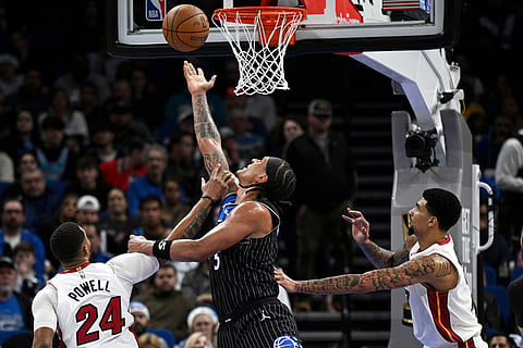 Orlando Magic forward Paolo Banchero (5) goes up to shoot between Miami Heat guard Norman Powell (24) and center Kel'El Ware, right, during the first half of an NBA Cup basketball game in Orlando, Florida. 