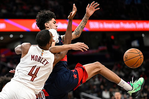 Cleveland Cavaliers center Evan Mobley (4) has his pass intercepted by Washington Wizards guard Will Riley, top, during the first half of an NBA basketball game in Washington. 