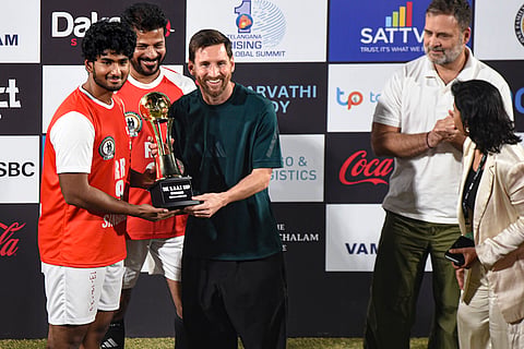 Argentine footballer and 2022 FIFA World Cup winning captain Lionel Messi presents a trophy to a young player during an event as part of the second leg of 'GOAT India Tour 2025', in Hyderabad.
