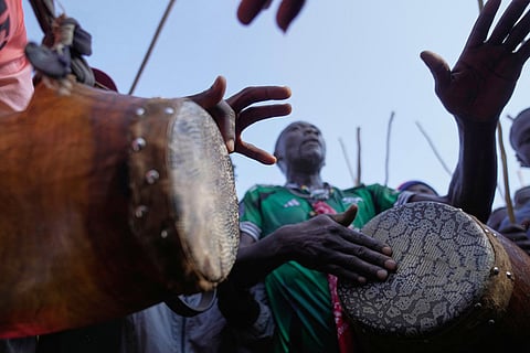 A crowd of spectators dances and sings "Isukuti," a traditional dance accompanied by a set of three drums, after bull Shakahola won bullfighting match, in Kakamega, Kenya.
