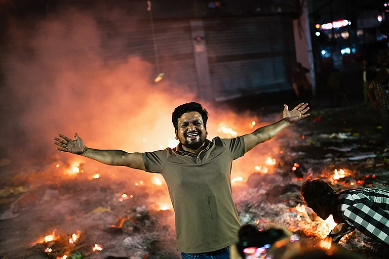 A protester reacts to the camera near the premises of the Prothom Alo daily newspaper which was set on fire by angry protesters after news reached the country from Singapore of the death of a prominent activist Sharif Osman Hadi, in Dhaka, Bangladesh. - | Photo: AP/Mahmud Hossain Opu