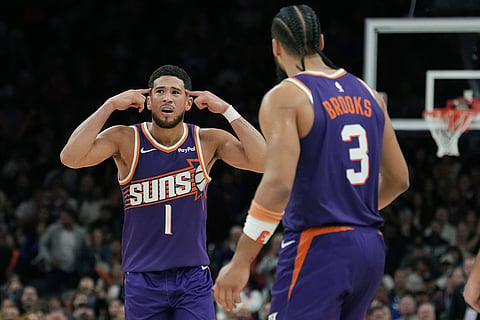 Phoenix Suns guard Devin Booker (1) signals to Suns forward Dillon Brooks (3) not to argue with officials during the second half of an NBA basketball game against the Golden State Warriors in Phoenix. 