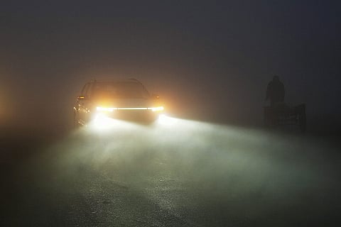 A car moves through dense fog on a winter morning, at Mayur Vihar area, in New Delhi. 