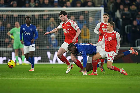Everton's Thierno Barry, bottom, is challenged by Arsenal's Leandro Trossard, right, and Declan Rice during the English Premier League soccer match between Everton and Arsenal in Liverpool, England.