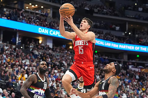 Houston Rockets guard Reed Sheppard, center, drives to the basket between Denver Nuggets guards Tim Hardaway Jr., left, and Bruce Brown, right, in the second half of an NBA basketball game in Denver. 