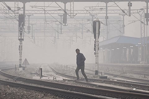 A man crosses a railway track amid low visibility on a winter morning, in Prayagraj.