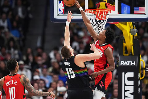 Houston Rockets guard Amen Thompson, right, blocks a shot by Denver Nuggets center Nikola Jokić as Houston forward Jabari Smith Jr. looks on in the second half of an NBA basketball game, in Denver. 