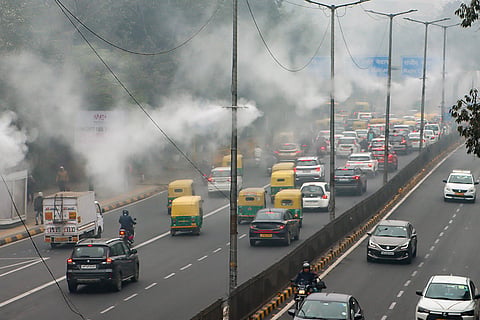 Water sprinklers operate under dense fog on a winter morning, in New Delhi.