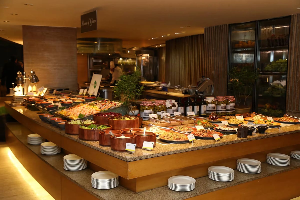 A long buffet counter with various dishes in bowls and platters under warm indoor lighting.