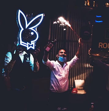 Staff celebrating at Playboy Club Chandigarh with neon logo and sparklers