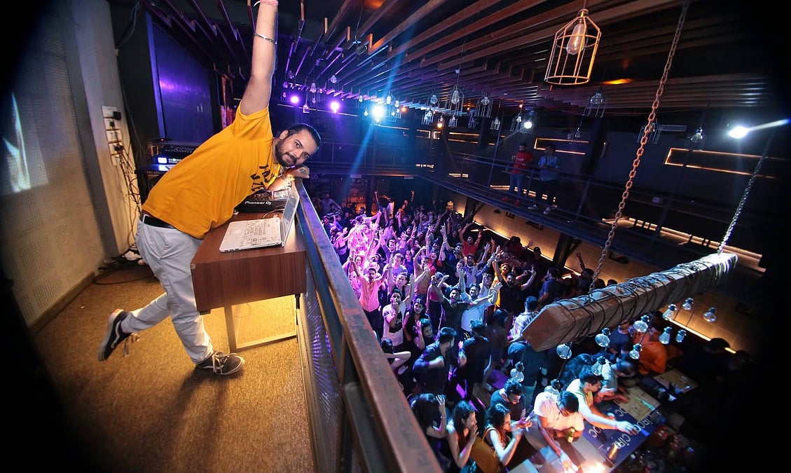 A DJ in a yellow shirt performs for a large crowd at Blackout Club and Terrace.