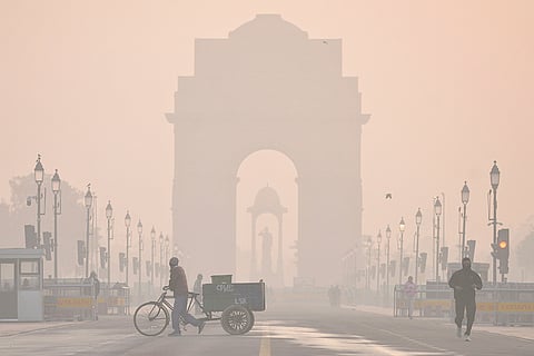 The India Gate shrouded in a layer of smog as people make their way during a cold winter morning, at Kartavya Path, in New Delhi. The national capital's Air Quality Index (AQI) moved to 'very poor' from 'severe' on Tuesday, according to the Central Pollution Control Board (CPCB).