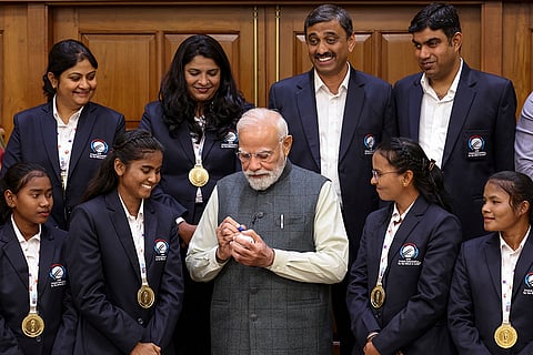 In this image released on Nov. 27, 2025, Prime Minister Narendra Modi signs a ball for members of the Indian Women's Cricket Team for the Blind, who recently won the inaugural T20 World Cup, during a meeting in New Delhi. 