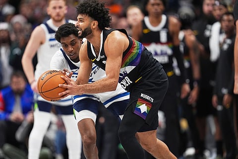 Denver Nuggets guard Jamal Murray, front, looks to pass the ball as Minnesota Timberwolves forward Jaden McDaniels defends in overtime of an NBA basketball game in Denver. 