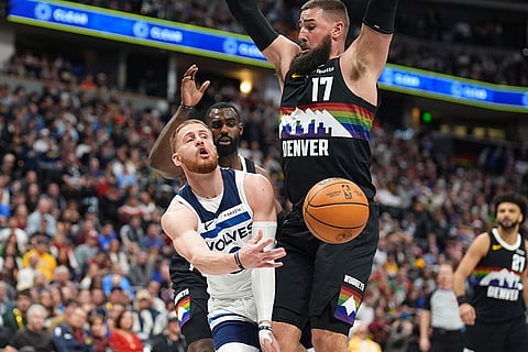 Minnesota Timberwolves guard Donte Divincenzo, front left, passes the ball after driving past Denver Nuggets guard Tim Hardaway Jr., back left, as center Jonas Valančiūnas defends in overtime of an NBA basketball game in Denver. 