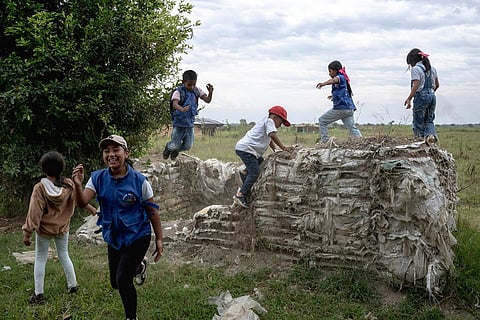 Young Indigenous guards play on the walls of an old military defense barrier made of sandbags, remnants of the military occupation in the area July, 19, 2025, in the Lopez Adentro reserve in Caloto, Colombia.
