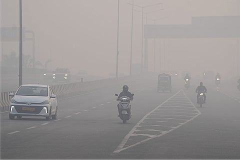 Commuters make their way amid dense smog, with hazy conditions reducing visibility on a winter morning, in New Delhi.