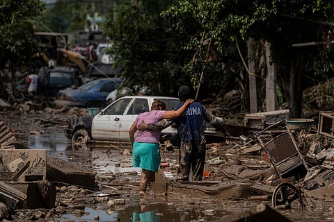 A Navy officer helps a woman cross a flooded street Oct. 12, 2025, in Poza Rica, Veracruz state, Mexico.