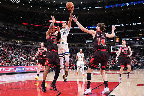 Milwaukee Bucks guard Ryan Rollins (13) drives to the basket against Chicago Bulls forward Isaac Okoro, left, and forward Matas Buzelis during the first half of an NBA basketball game in Chicago.