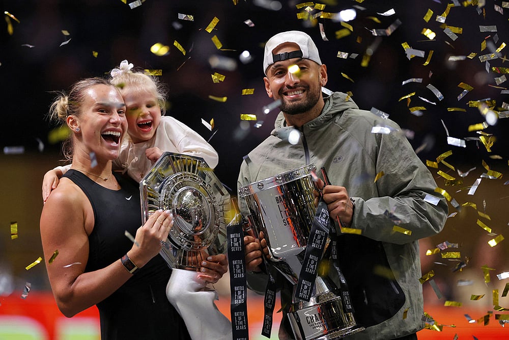 | Photo: Amr Alfiky/Pool Photo via AP : Aryna Sabalenka holds her goddaughter next to Nick Kyrgios as they pose with trophies after their Battle of the Sexes tennis match, in Dubai, United Arab Emirates.