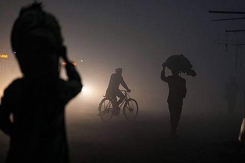People cross a road amid dense fog on a winter morning, in New Delhi.