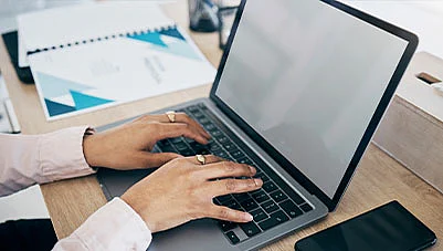 Hands typing on a laptop with a financial bar chart in the background.