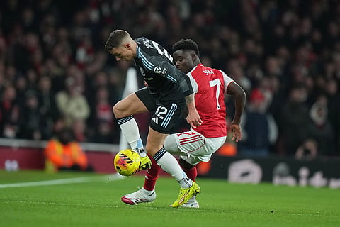 Aston Villa's Lucas Digne, left, challenges for the ball with Arsenal's Bukayo Saka during the English Premier League soccer match between Arsenal and Aston Villa in London.