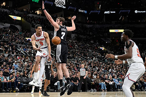 New York Knicks guard Kevin McCullar Jr. (9) passes to Knicks center Ariel Hukporti as he is guarded by San Antonio Spurs center Luke Kornet (7) during the first half of an NBA basketball game in San Antonio.
