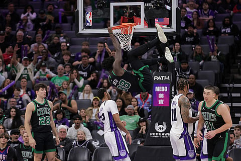 Boston Celtics center Neemias Queta (88) hangs on the rim after dunking the ball during the second half of an NBA basketball game against the Sacramento Kings, in Sacramento, California.