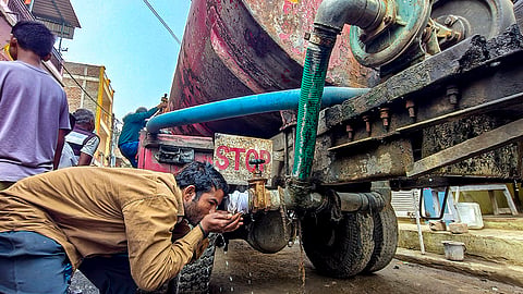 A man drinks water from a tanker amid a contaminated water crisis at Bhagirathpura, in Indore.