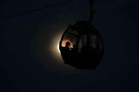A cable car passenger is silhouetted against a rising super wolf moon in Caracas, Venezuela.