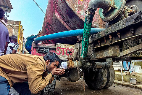 A man drinks water from a tanker amid a contaminated water crisis at Bhagirathpura, in Indore.