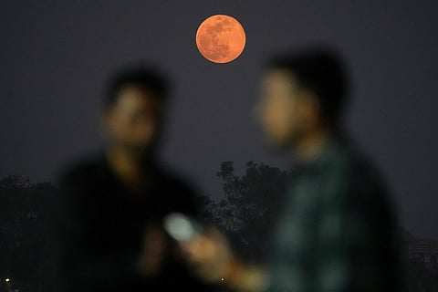 Two men talk as a Wolf Supermoon rises in Ahmedabad, India.