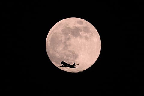 A plane passes in front of a Wolf Supermoon in Chicago.