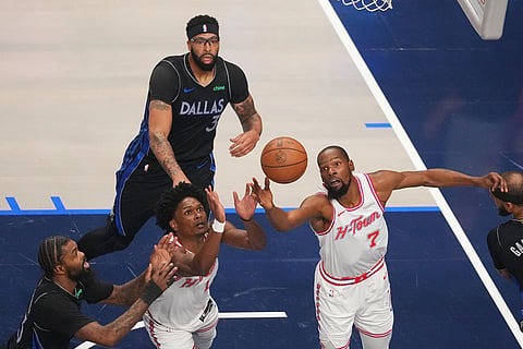 Houston Rockets forward Kevin Durant (7) and teammate guard Amen Thompson (1) compete for a rebound against Dallas Mavericks forward Anthony Davis, top, and forward Naji Marshall, left, during the first half of an NBA basketball game in Dallas.