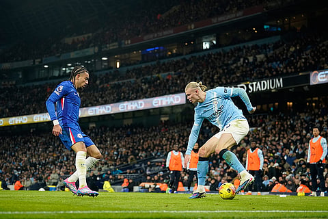 Manchester City's Erling Haaland, right, dribbles the ball in from of Chelsea's Malo Gusto during the English Premier League soccer match between Manchester City and Chelsea in Manchester, England.