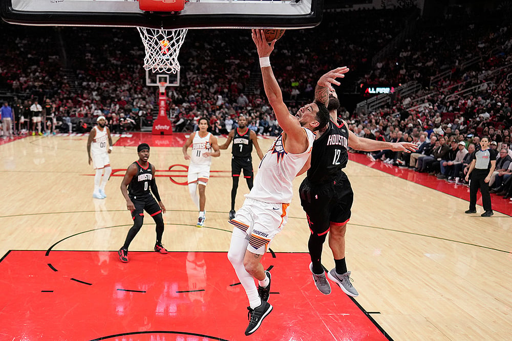 Phoenix Suns' Devin Booker (1) goes up for a shot as Houston Rockets' Steven Adams (12) defends during the second half of an NBA basketball game in Houston.  - | Photo: AP/David J. Phillip