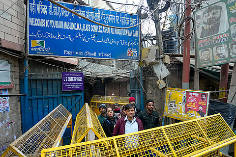 People stand at the entrance of a street closed with barricades after a demolition drive of alleged encroachments from a land adjoining the Syed Faiz Elahi mosque and a nearby graveyard carried out by the Municipal Corporation of Delhi (MCD), at Turkman Gate area, in New Delhi.