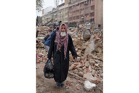 An elderly man walks through the debris after a court-mandated demolition on land adjoining the Syed Faiz Elahi Mosque and a nearby graveyard, in New Delhi.