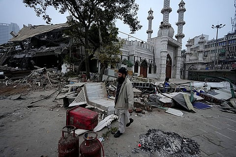 A man walks past belongings lying on a road after the demolition of alleged encroachments from a land adjoining the Syed Faiz Elahi mosque carried out by the Municipal Corporation of Delhi (MCD), at Turkman Gate area, in New Delhi.