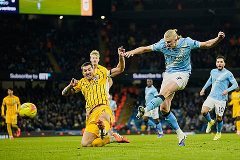 Manchester City's Erling Haaland, right, attempts a shot at goal in front of Brighton's Lewis Dunk during the English Premier League soccer match between Manchester City and Brighton and Hove Albion in Manchester, England.