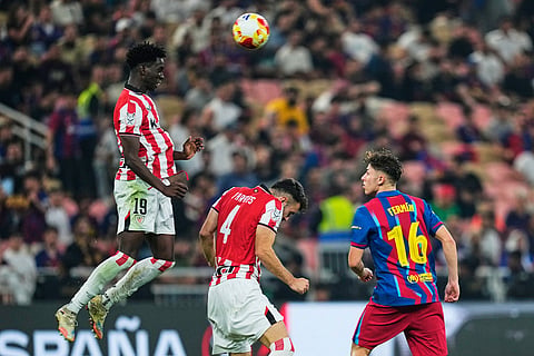 Athletic Bilbao's Adama Boiro heads the ball next to Athletic Bilbao's Aitor Paredes, center, and Barcelona's Fermin Lopez, right, during the Spanish Super Cup semifinal soccer match at King Abdullah Sports City Stadium in Jeddah, Saudi Arabia.