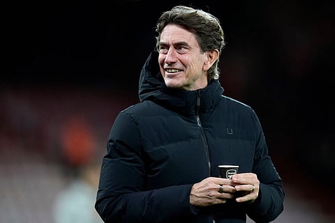Tottenham Hotspur manager Thomas Frank holds a coffee cup bearing the Arsenal logo as he walks on the pitch before the English Premier League soccer match between Bournemouth and Tottenham Hotspur in Bournemouth, England.