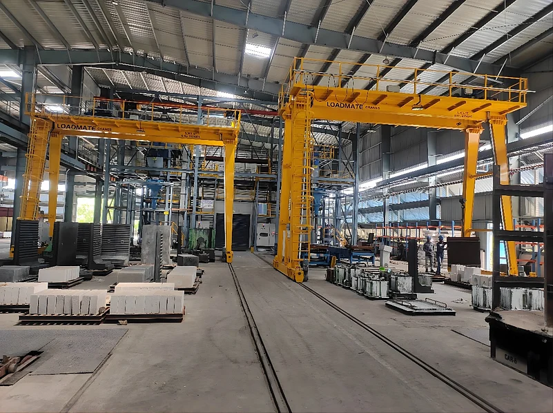 Two yellow industrial gantry cranes inside a manufacturing facility