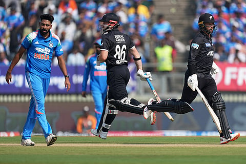 New Zealand's Devon Conway, right, and batting partner Henry Nicholls run between the wickets as India's Mohammed Siraj, left, looks on during the first One Day International cricket match between India and New Zealand in Vadodara, India.