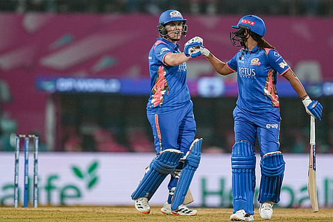 Mumbai Indians' captain Harmanpreet Kaur, right, and Nat Sciver-Brunt interact between the wickets during a Women's Premier League (WPL) T20 cricket match between Mumbai Indians and Delhi Capitals, at the DY Patil Stadium, in Navi Mumbai.