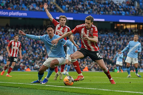 Manchester City's Tijjani Reijnders, left, and Exeter's Jack Fitzwater fight for the ball during the FA Cup third round match between Manchetster City and Exeter in Manchester, England.