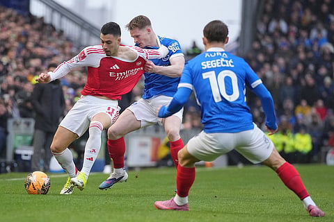 Arsenal's Gabriel Martinelli, left, and Portsmouth's Terry Devlin fight for the ball during the FA Cup third round soccer match between Portsmouth and Arsenal in Portsmouth, England.