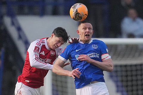 Arsenal's Gabriel Martinelli, left, and Portsmouth's Colby Bishop jump for the ball during the FA Cup third round soccer match between Portsmouth and Arsenal in Portsmouth, England.